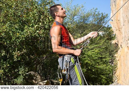 Climbing Equipment On A Male Climber: Rock Shoes, Rope, Quickdraw, Safety Device, Harness. Sports Mo