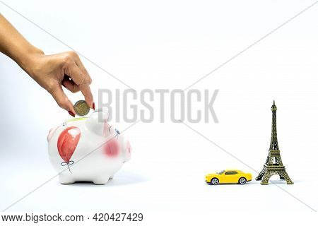 Travel Or Vacation Money Saving Concept. Hand Hold Coin, Pink Piggy Bank With Car And Eiffel Tower I