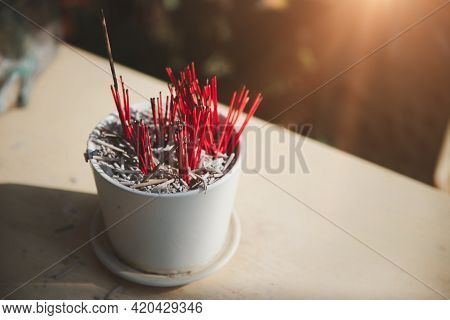 White Ceramic Incense Burner Or Joss Stick Pot With Several Red Incenses Stems Adorned To Worship Th