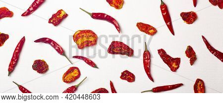 Peppers And Tomatoes Banner Background. Dried Hot Chili Peppers And Red Sun-dried Tomatoes On A Whit