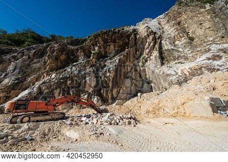 Orange Tracked Excavator In A White Marble Quarry. Apuan Alps (alpi Apuane), Massa And Carrara Provi