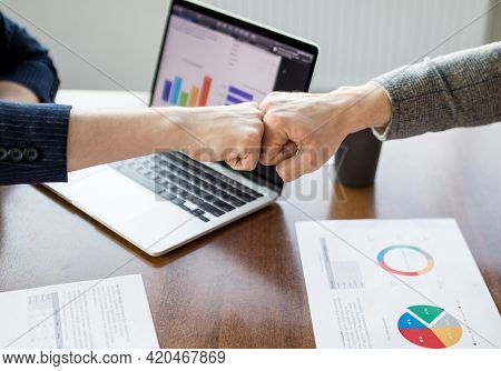 Close Up Of Young Businessman And Businesswoman Making The Fist Bump On Building Background. Busines