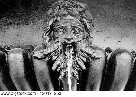 Fountain With A Statue Of A Mans Head, Water Flows From His Mouth