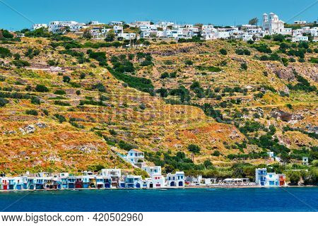 Klima and Plaka villages with whitewhashed traditional houses and orthodox church and windmills on Milos island, Greece