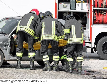 Firefighters At The Rescue To The Injured With A Stretcher After The Car Accident