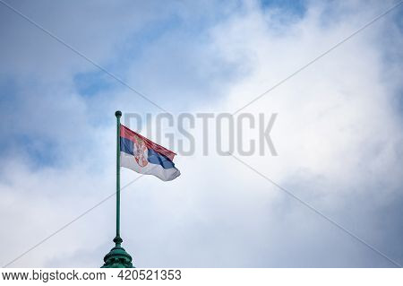 Photo Of The Official Flag Of The Republic Of Serbia, With A Backround Of Blue Sky And Clouds. Serbi
