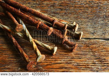 A Close Up Image Of Several Old And Rusted Carpentry Nails On A Dark Wooden Nails.