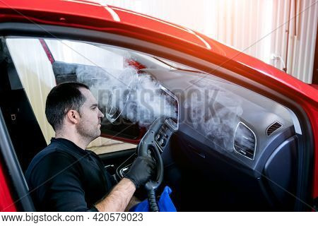 Car Service Worker Cleans Interiror With Steam Cleaner