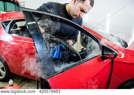 Car Service Worker Cleans Interiror With Steam Cleaner