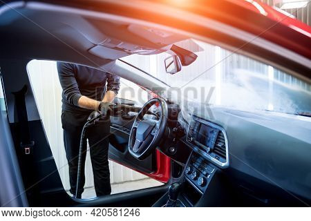 Car Service Worker Cleans Interiror With Steam Cleaner