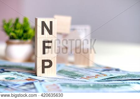 Wooden Cubes With The Letters Nfp Arranged In A Vertical Pyramid On Banknotes, Concept