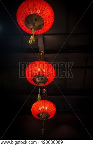 Traditional chinese lanterns hanging from the ceiling. Bright red chinese decorative lamps displayed against dark background.