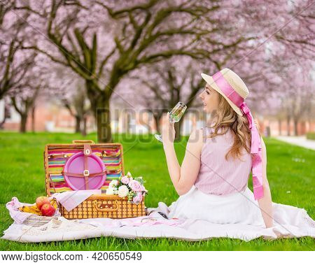 Beautiful Woman In Straw Hat Under Blooming Cherry Trees In Picnik Place. Girl Wearing A Pink Long S