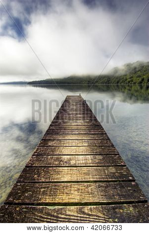 Lugn sjö med dimma och båt docka