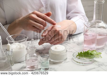 Scientist Testing Cosmetic Product At White Marble Table In Laboratory, Closeup