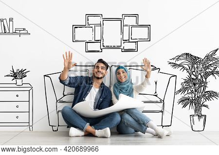 Happy Muslim Family Sitting On Floor With Apartment Scheme