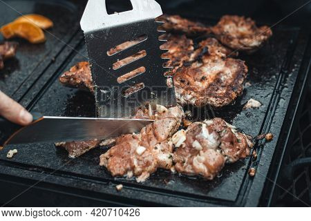 Man Slices A Pork Neck, Fragrant And Richly Seasoned With Basil, Pepper, Salt And Other Herbs, Which