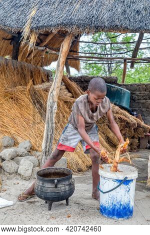 Portrait of an hungry African child boiling some roots in a pot in their kitchen yard in a village  in Botswana village
