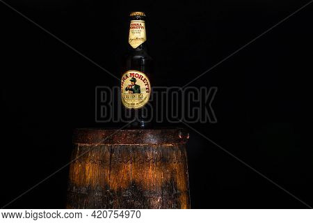Bottle Of Birra Moretti Beer On Wooden Barrel With Dark Background. Illustrative Editorial Photo Buc