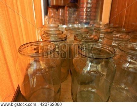 Old Style Empty Glass Jars On Shelf Behind Orange Curtain