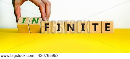 Finite Or Infinite Symbol. Businessman Turns Wooden Cubes And Changes The Word 'finite' To 'infinite