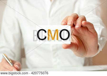 A Woman In A White Shirt Holds A Piece Of Paper With The Text: Cmo. Business Concept For Companies. 
