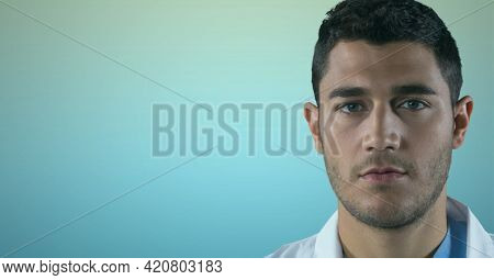 Portrait of caucasian male doctor against blue gradient background. healthcare and medical research technology concept