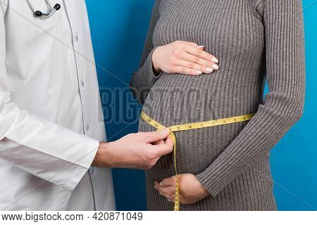 Happy Beautiful Pregnant Young Woman Touching Her Bare Tummy While A Doctor Is Measuring It