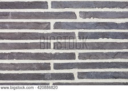 A Rhythmic Look Of Gray Horizontal Stone Slabs Embedded In The Wall With Wide Cement Joints.