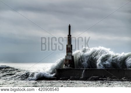 Giant Waves Breaking On The Breakwater And The Lighthouse On Aguda Beach, Miramar, Arcozelos Town