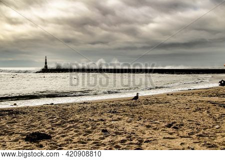 Giant Waves Breaking On The Breakwater And The Lighthouse On Aguda Beach, Miramar, Arcozelos Town