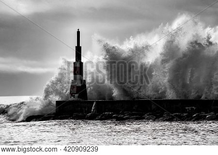 Giant Waves Breaking On The Breakwater And The Lighthouse On Aguda Beach, Miramar, Arcozelos Town