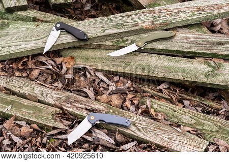 Several Different Pocket Knives. Pocket Knives On A Wooden Background. Knives Of Various Shapes. Top