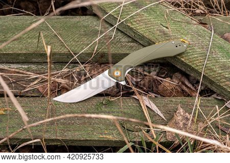 A Knife For Everyday Use Lying On Wooden Sticks. Folding Pocket Knife. Top.