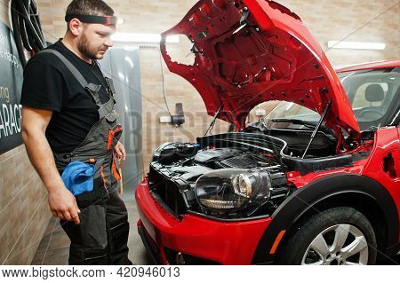 Car Service Worker Put Anti Gravel Film On A Red Car Body At The Detailing Vehicle Workshop. Car Pro