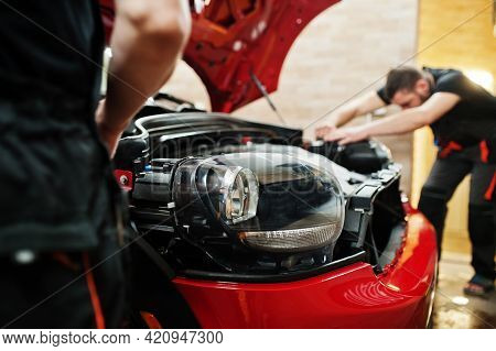 Car Service Worker Put Anti Gravel Film On A Red Car Body At The Detailing Vehicle Workshop. Car Pro