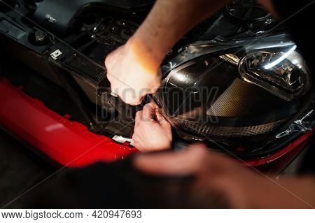 Car Service Worker Put Anti Gravel Film On A Red Car Body At The Detailing Vehicle Workshop. Car Pro