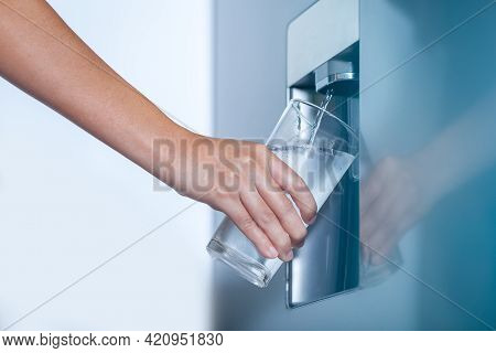 Water Dispenser From Dispenser Of Home Fridge, Woman Is Filling A Glass With Water From The Refriger
