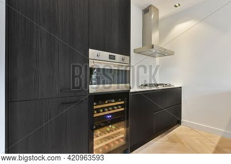 Interior Of Corner Of Contemporary Kitchen With Dark Wooden Cupboard And Cabinet Equipped With Moder