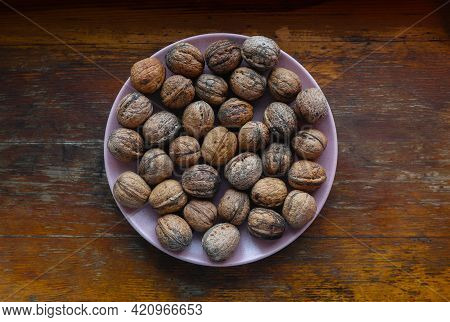 A Handful Of Walnuts On A Pink Plate. High Quality Photo