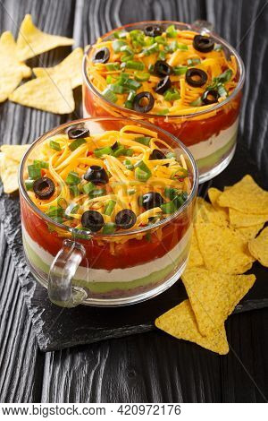 Mexican Seven Layer Dip Salad Served With Chips Close-up On The Table. Vertical