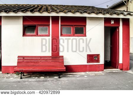 Red And White Beach Hut With A Red Bench On The Aguda Beach In A Sunny Day Of January