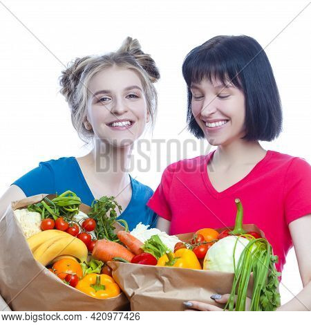 Healthy Lifestyle. Portrait Of Two Young Caucasian Girls Posing With Paper Bag Filled Grocery And Ve