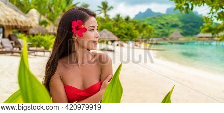 Beach beauty woman Natural exotic babe in red swimsuit looking serene on tropical beach. Asian bikini model wearing hibicus flower for body care pampering.