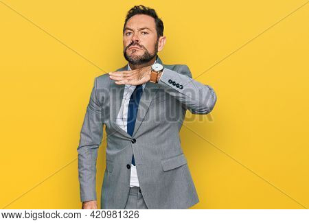 Middle age man wearing business clothes cutting throat with hand as knife, threaten aggression with furious violence 