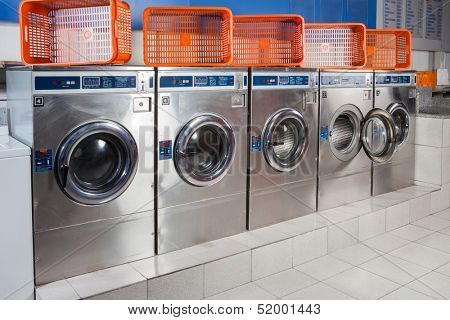 Washing machines and empty baskets in a row at laundromat