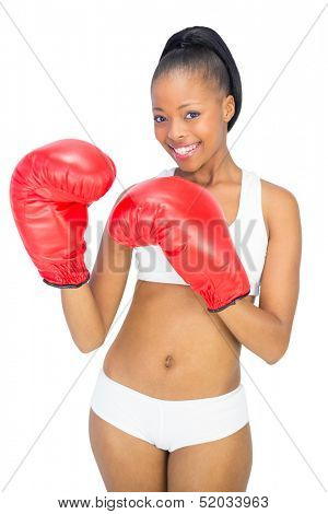 Competitive smiling model wearing red boxing gloves against white background