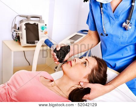 Doctor giving oxygen mask to female patient at hospital.