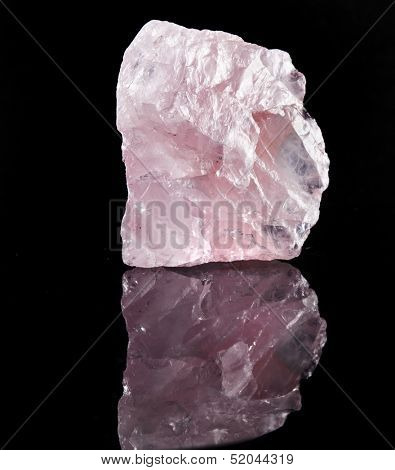 Natural Rose Quartz crystal with reflection on black surface background 