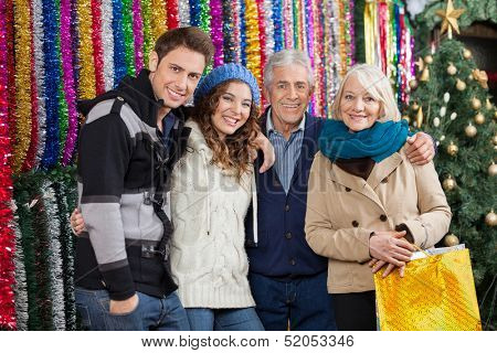 Portrait of happy family standing together against tinsels at Christmas store